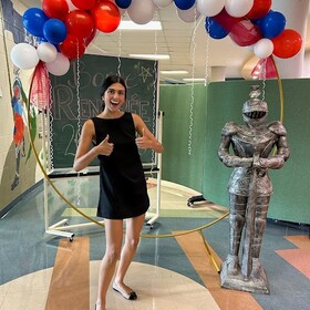 Rentrée à l'école, une membre du personnel sourit devant une banderole de ballons